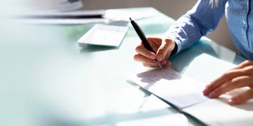 A man signing a document by hand