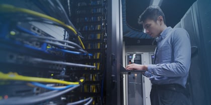 Data center technician working with servers and network equipment inside a modern data center, illustrating how to become a data center technician, salary, and required certifications.