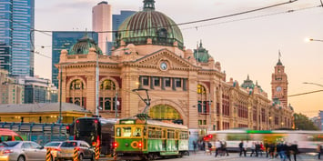 A vintage green and gold tram passes in front of Flinders Street Station in Melbourne, Australia