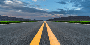 Straight road leading toward mountains under a vibrant sky, symbolising planning for the future 