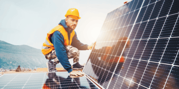 Worker in hi-vis and hardhat stood on solar panel