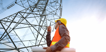  Engineer with hardhat and plans under electricity pylon