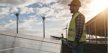 Energy workers in front of solar panels and wind turbines in Australia.